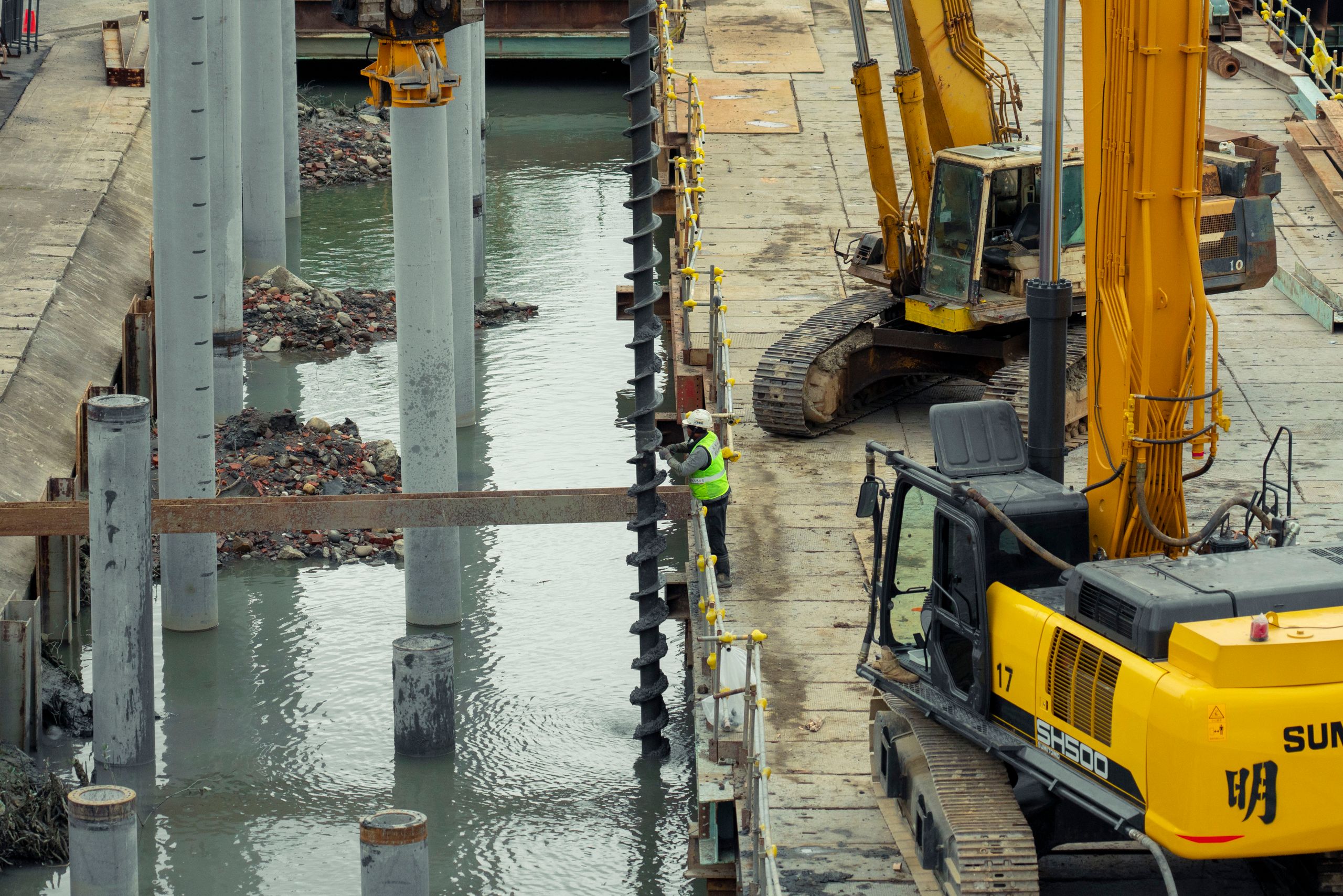 A construction site in Taipei, Taiwan, featuring heavy machinery and a worker on site.